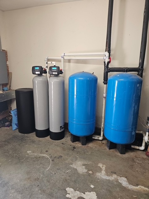 Modern residential water treatment system with stainless tanks and blue piping